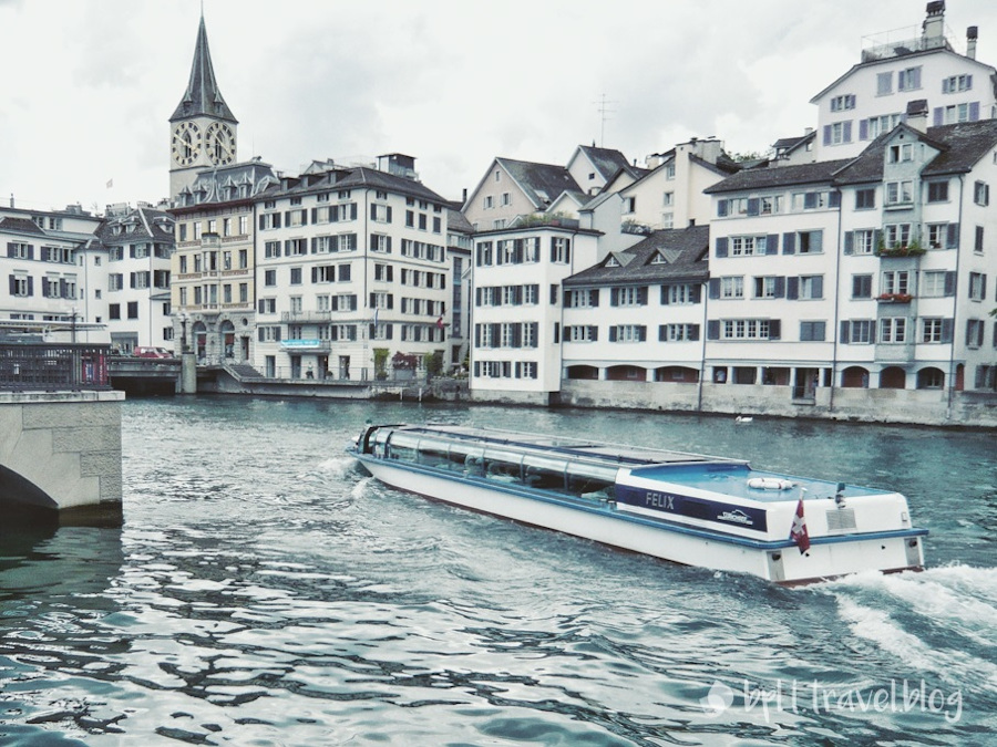 The clock face of St. Peter and the Limmat River Cruise boat in Zurich.